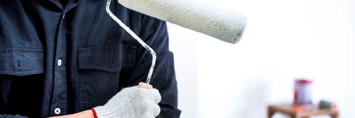 Male Painter with arm crossed holding paint roller, Interior working with paint roller in room, shape and structure.